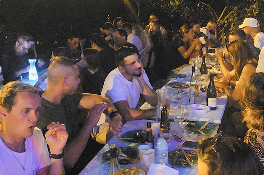 Collaborateurs EI Groupe partageant un dîner convivial en extérieur à la tombée de la nuit lors d'un séminaire d'été