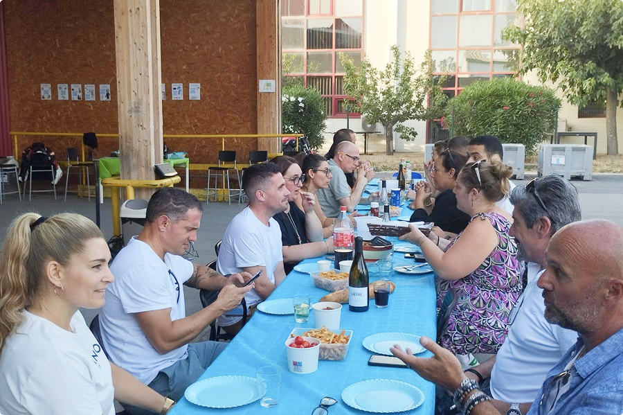 Collaborateurs EI Groupe réunis autour d'un grand repas convivial en plein air lors d'un afterwork d'été