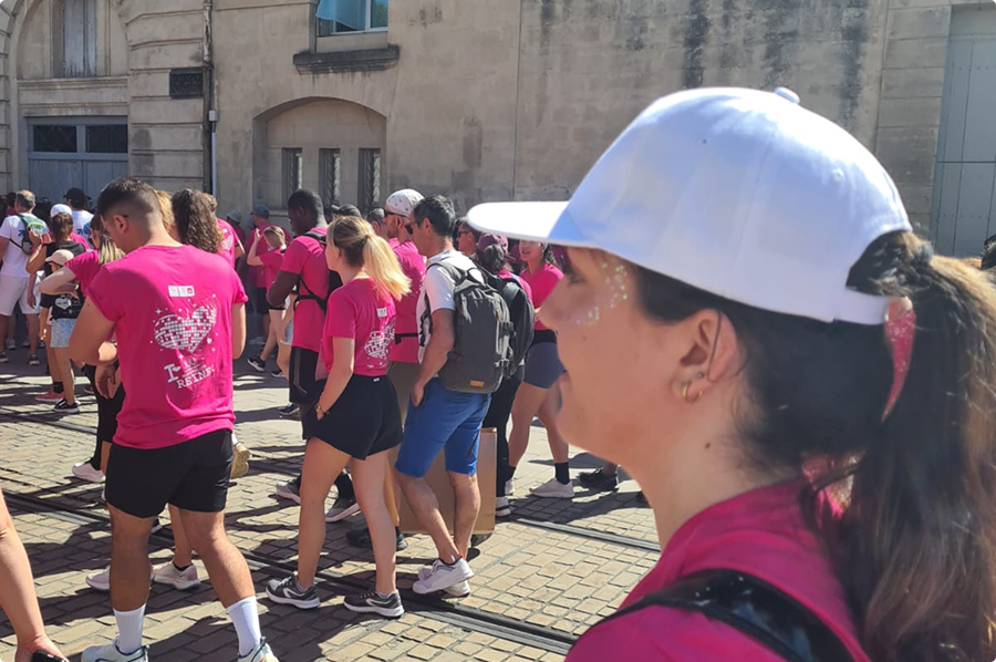 Collaboratrice EI Groupe en t shirt rose suivant le cortège d'une course solidaire dans les rues de Montpellier