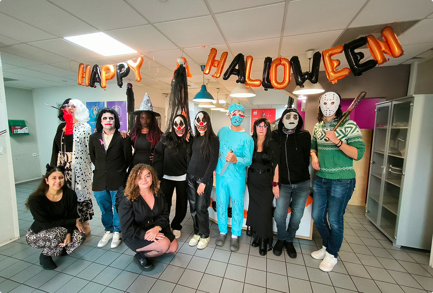 Collaborateurs EI Groupe déguisés posant en groupe sous une banderole « Happy Halloween » dans les locaux