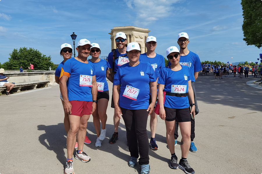 Équipe EI Groupe en t shirts bleus et dossards posant devant le château d'eau du Peyrou à Montpellier